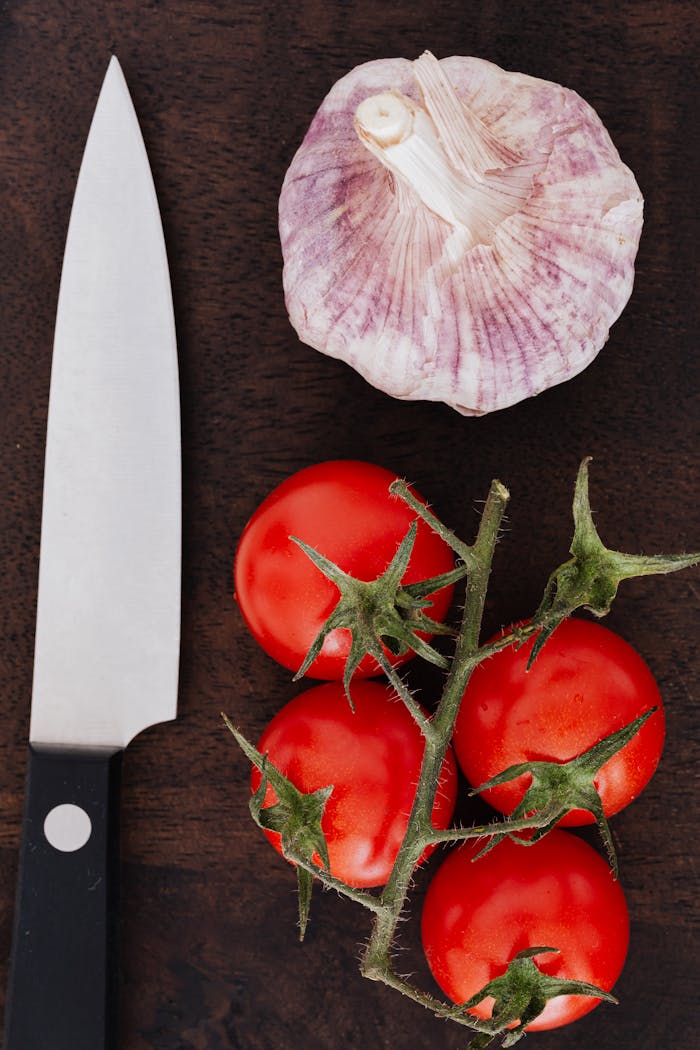 Tomatoes and garlic and knife on cutting board