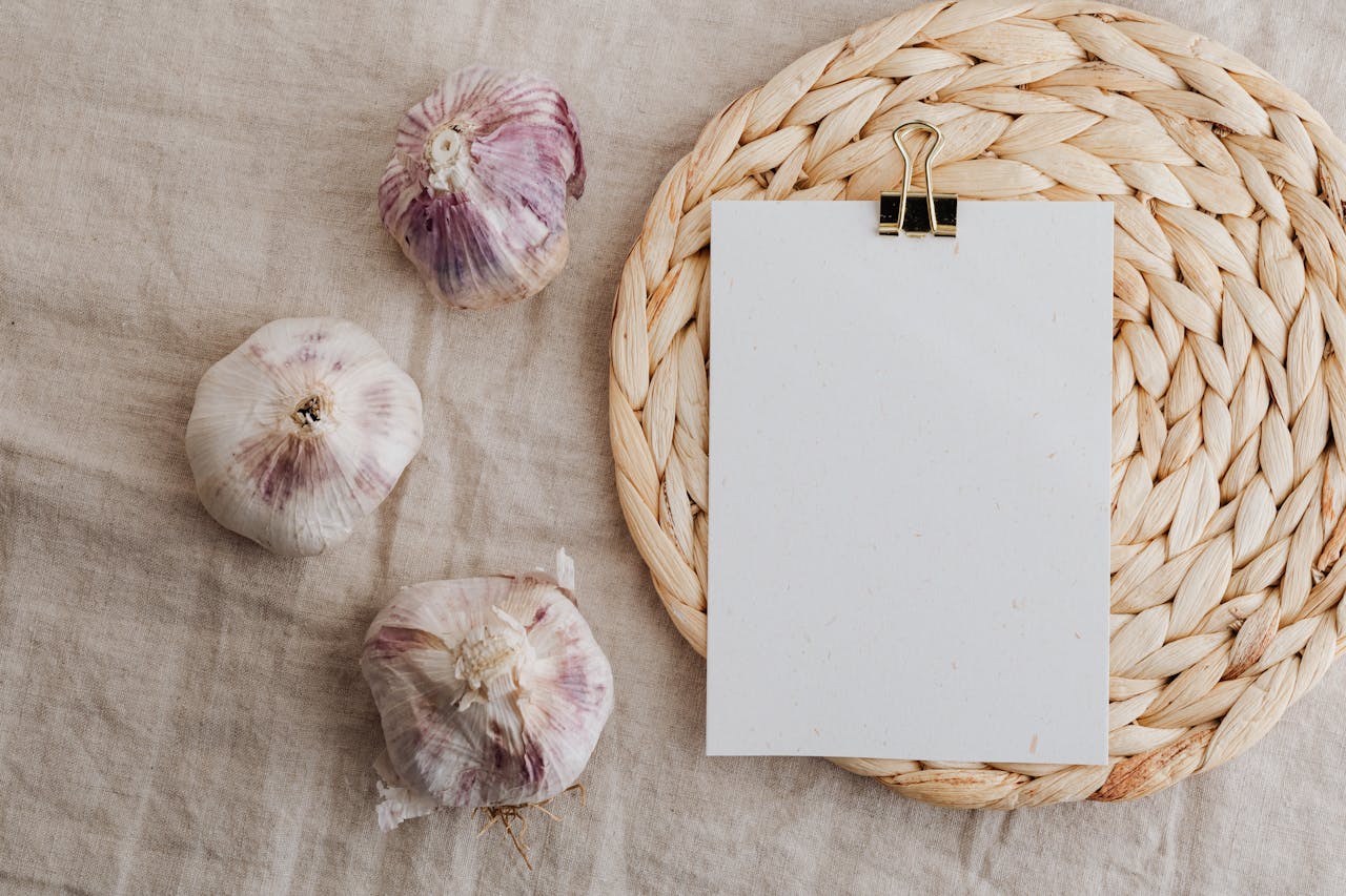 Garlic and blank paper over wicker placemat on white tablecloth